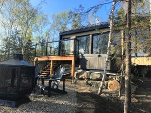 une maison dans les bois avec un banc devant elle dans l'établissement Charlevoix expérience thermale en pleine nature - Suites Nature Charlevoix - Suite #2, aux Éboulements