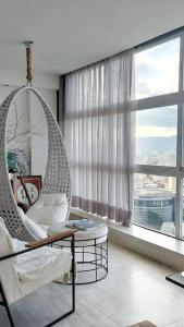 a living room with a swinging chair and a large window at Apto Varandas no andar 38 ,abaixo do SampaSKY in Sao Paulo