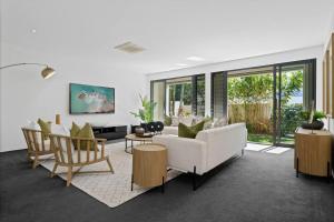 a living room with a white couch and chairs at Witta Circle - Walk to Hastings St & Noosa Beach in Noosa Heads