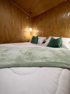 a bedroom with a large bed with green and white pillows at Refugio El Chucao in Hornopiren