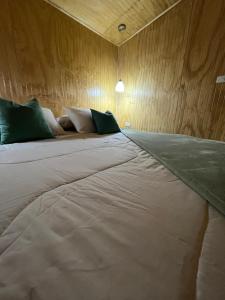 a large bed in a room with a wooden wall at Refugio El Chucao in Hornopiren