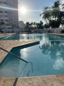 a swimming pool with blue water in a city at Ocean Front Condo in Isla Verde! in San Juan