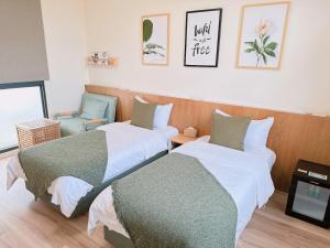 a room with two beds and a chair at Gardenstay in Luodong