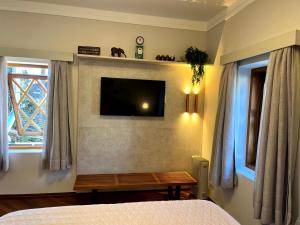 um quarto com uma televisão numa parede com uma mesa em Flat Centro de Capivari em Campos do Jordão