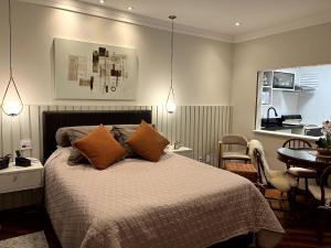 a bedroom with a bed and a table and chairs at Flat Centro de Capivari in Campos do Jordão