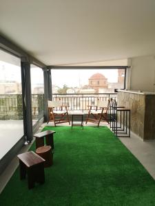 einen Balkon mit grünem Gras, Tischen und Bänken in der Unterkunft Domi's Rooftop Apartment in Thessaloniki