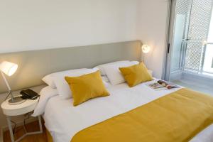 1 dormitorio con 1 cama con almohadas amarillas y blancas en Mérit Montevideo Apart & Suites, en Montevideo