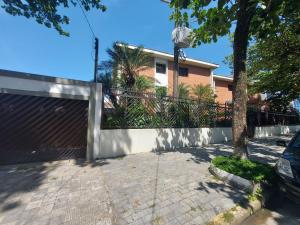 a fence in front of a house with a driveway at Apto aconchegante pé na areia in Guarujá