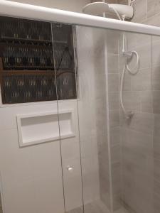a shower with a glass door in a bathroom at Apto aconchegante pé na areia in Guarujá +23 photos