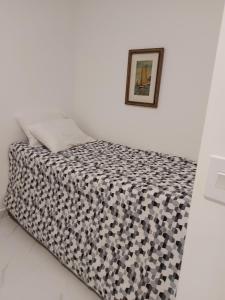 a bed with a black and white comforter in a room at Apto aconchegante pé na areia in Guarujá