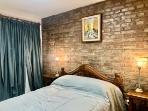Un dormitorio con una pared de ladrillo y una cama en Quinta Parque Mendoza en Mendoza