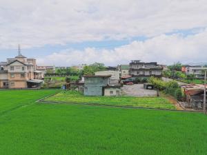 uma vista para uma aldeia com relva verde e edifícios em Gardenstay em Luodong