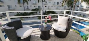 uma varanda com cadeiras, uma mesa e uma piscina em Departamento Confortable y Moderno en Acapulco Diamante em Acapulco