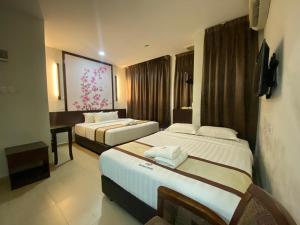 um quarto de hotel com duas camas e uma secretária em D&F BOUTIQUE HOTEL SENAWANG em Senawang