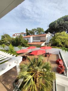 balkon ze stołami, czerwonymi parasolami i oceanem w obiekcie Embaixada da Vila w mieście Cascais