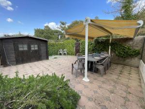 a table and chairs under an umbrella on a patio at Maison rénovée 5 pièces, jardin clos, à 2 pas de l'océan, pour 10 personnes - Saint-Jean-de-Monts - FR-1-224C-231 in Saint-Jean-de-Monts
