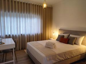 a bedroom with a bed with a desk and a window at Embaixada da Vila in Cascais