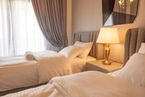a hotel room with two beds and a lamp at HOOUD Apartments in Khor Fakkan