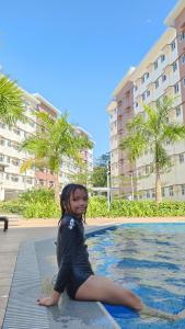 a young girl sitting on the edge of a swimming pool at Apparate Condotel Staycation in Cavite