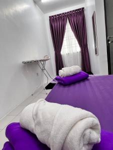 two beds in a room with purple sheets and a window at Raina Muslim Homestay Perlis in Arau