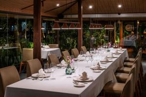 a long table in a restaurant with white tables and chairs at Farmhouse Resort & Spa in Kampong Chhnang
