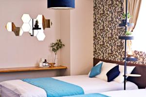 Dos camas en una habitación de hotel con azul y blanco en Tommy Condominium WAKASA301, en Kume