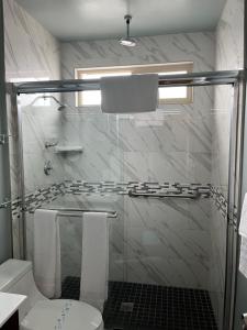 a white bathroom with a shower and a toilet at 777 Motor Inn in Huntington Beach