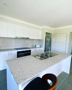 una cucina con armadi bianchi, lavandino e bancone di Camellia Cottage Pet Friendly Farm Stay a Picton