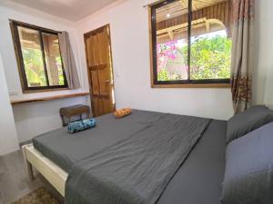 a bedroom with a bed and two windows at Treehouse Front Beach Bacong in Bacong