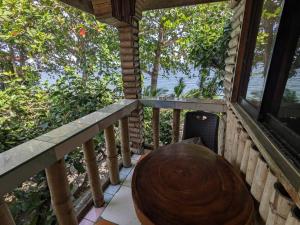 a table and chair on a porch with a view of the water at Treehouse Front Beach Bacong in Bacong