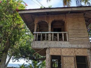 a building with a balcony on top of it at Treehouse Front Beach Bacong in Bacong