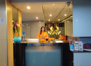 Una donna in piedi dietro un bancone in una cucina di Cozi Inn Hotel, Bangkok a Bangkok