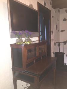 a tv on top of a wooden cabinet with flowers on it at Casa rural Adoracion Chipude - Adults Only in Chipude
