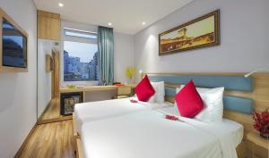 a bedroom with a large white bed with red pillows at RAMADA ENCORE BY WYNDHAM SAIGON D1 - Formerly M Boutique Hotel Saigon in Ho Chi Minh City