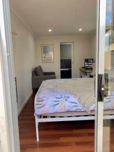 a bedroom with a bed and a living room at GARDEN CUBBY - The Lakeside Haven in Lake Illawarra