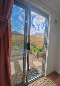 a sliding glass door with a view of a yard at GARDEN CUBBY - The Lakeside Haven in Lake Illawarra