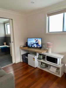 a living room with a television on a table at GARDEN CUBBY - The Lakeside Haven in Lake Illawarra