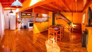 a room with a table and a kitchen with yellow walls at Cabaña de las Flores in Tolhuin