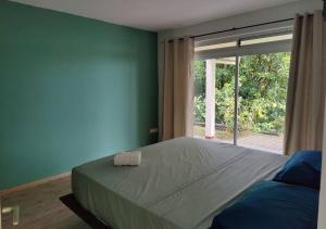 um quarto com uma cama grande e uma janela grande em Logement cozy avec Jardin em Arue