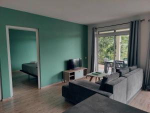 uma sala de estar com um sofá e um quarto com uma televisão em Logement cozy avec Jardin em Arue