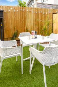 a white table and chairs on a lawn with a fence at The Majestic retreat 2 bed 2 bath CBD in Christchurch