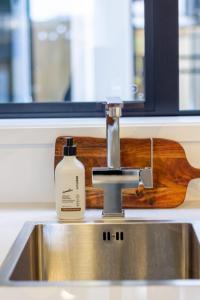 a sink with a bottle of soap sitting on top of it at The Majestic retreat 2 bed 2 bath CBD in Christchurch