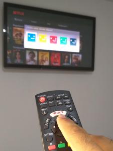 a persons hand holding a remote control in front of a tv at Confort 13-47 in Cali