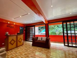 a living room with red walls and a couch andwindows at Mistico Machupicchu Eco B&B in Machu Picchu