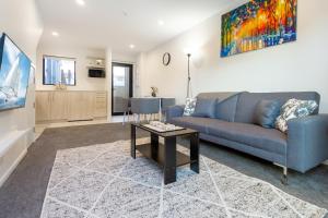 a living room with a blue couch and a table at Wave side escape 1 bed 1 bath, New Brighton in Christchurch