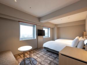 秋田市にあるANAクラウンプラザホテル秋田のベッドとテーブルが備わるホテルルームです。