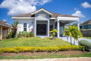 una casa blanca con un patio verde en Luxurious 3-BDRM/King Bed/Gated/Near Ocho Rios, en Boscobel