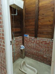 a bathroom with a toilet in a brick wall at Traveller Mountain Spring Farm in Beipu