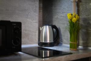 a coffee pot on a counter with a vase of flowers at Смарт-студія в центрі біля парку in Uzhhorod