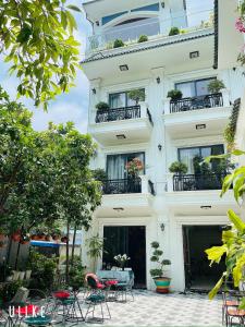 a white building with chairs and tables in front of it at Lynh's Villa in Cat Ba